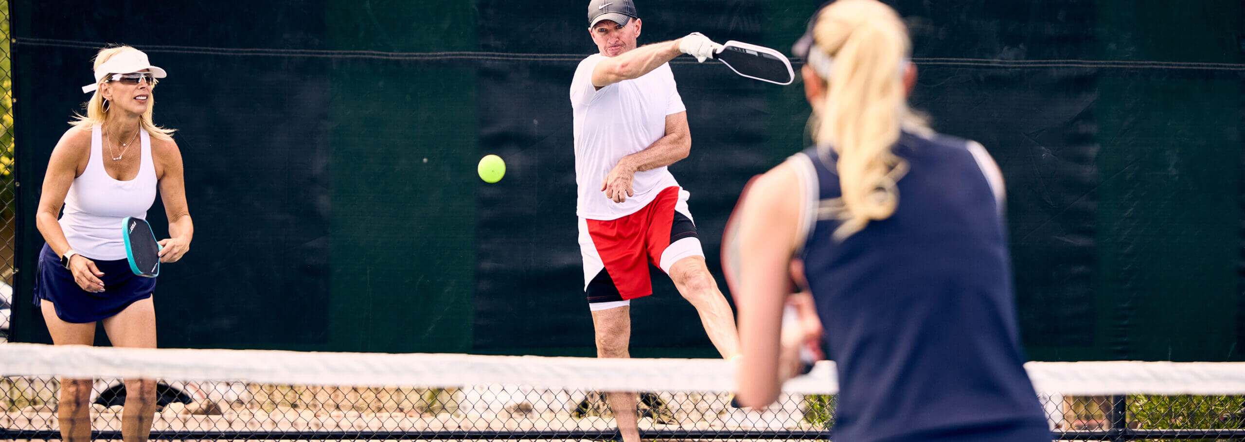 Members play pickleball outdoors at Village Clubs Camelback, enjoying a friendly match on the pickleball courts.