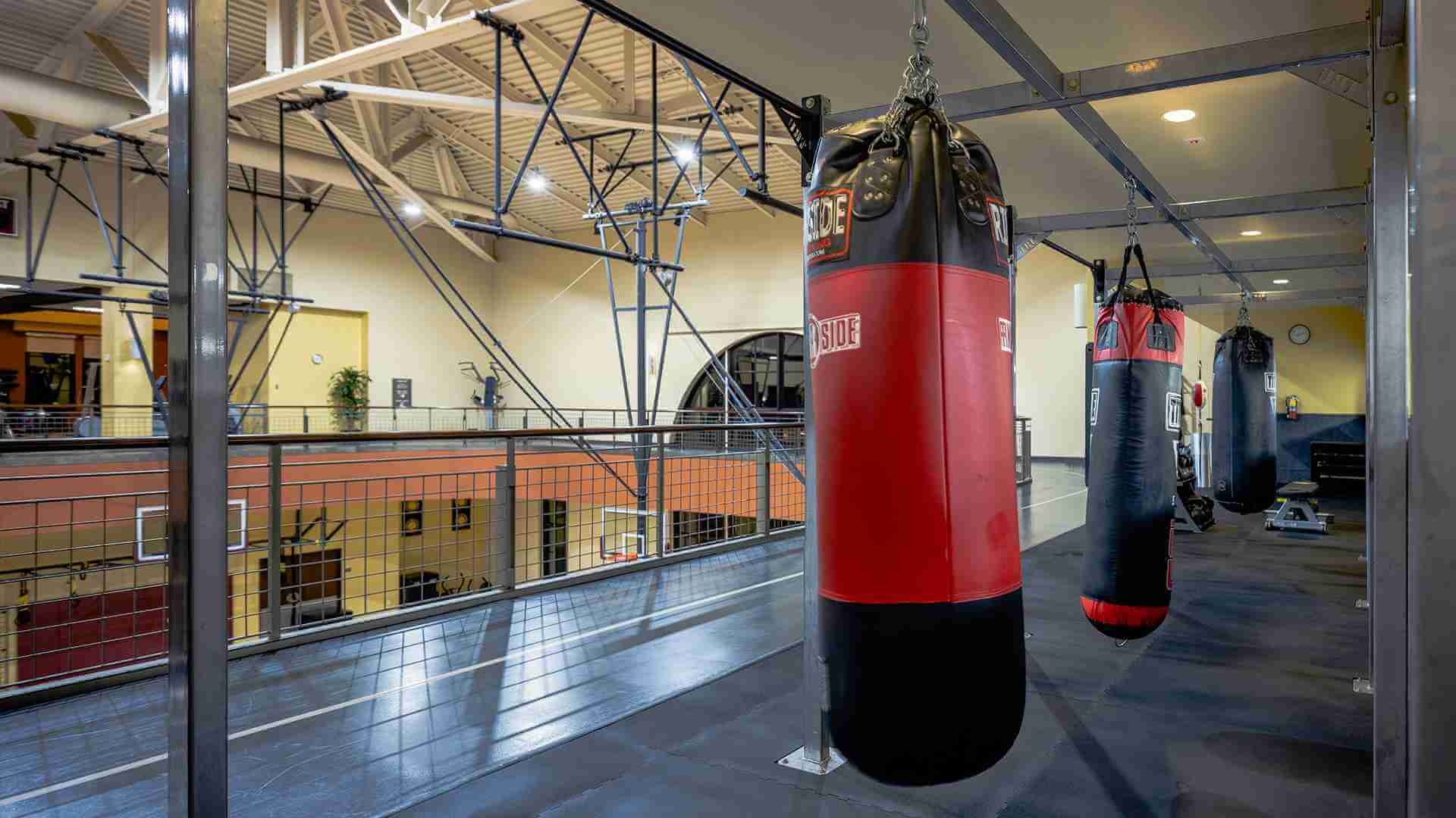 Village Clubs DC Ranch gym features black and red punching bags, high ceilings, large windows, and an indoor balcony.