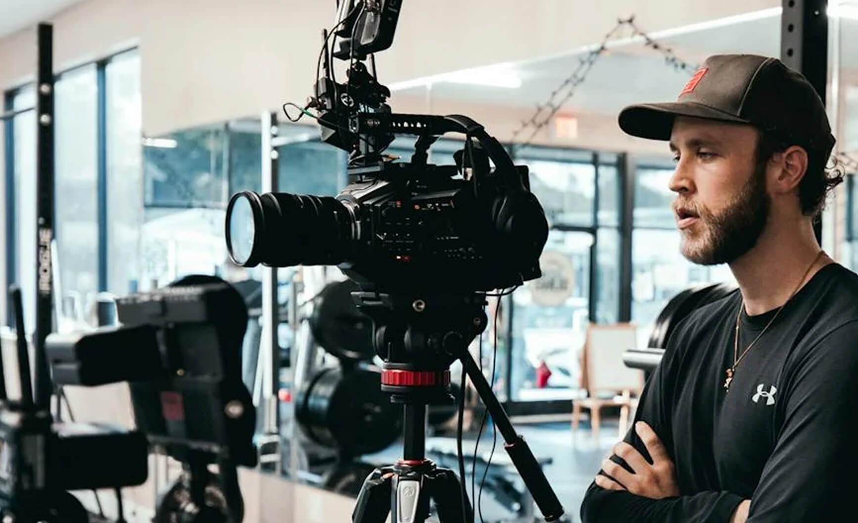 A man prepares video equipment at Village Clubs Camelback, focused on setting up for an indoor filming or event coverage.