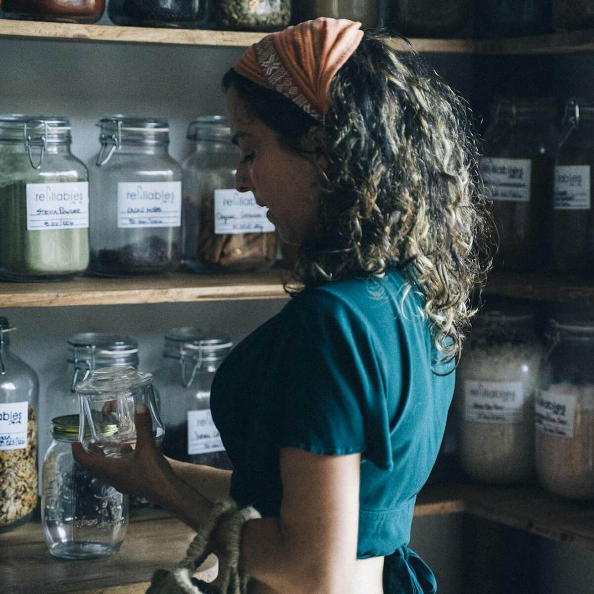 A woman at Village Clubs DC Ranch organizes pantry shelves filled with jars, enjoying exclusive member benefits and a tidy space.