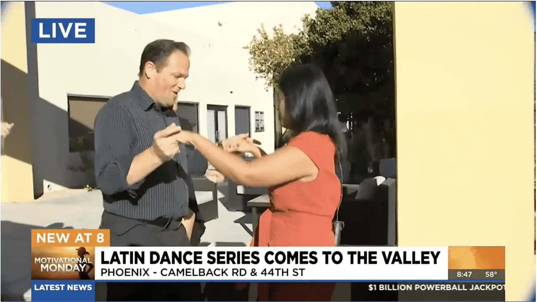 A man and woman dance Latin style outside Village Clubs Camelback, promoting the Latin Dance Series in Phoenix. News segment banner shown.