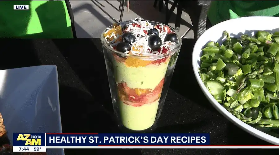 Village Clubs Camelback: Colorful parfait with blueberries and coconut beside greens, promoting Healthy St. Patrick's Day recipes on TV.