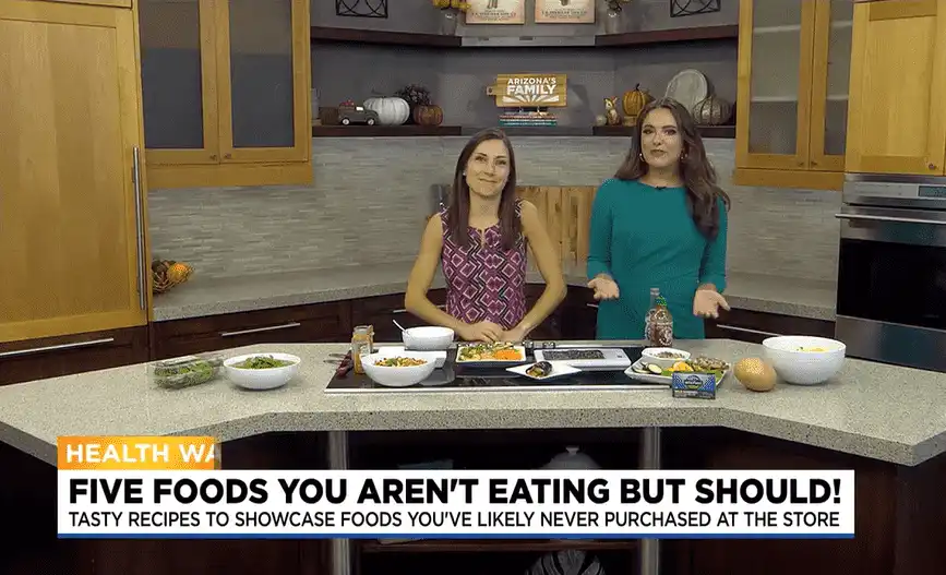 Two women at Village Clubs Camelback kitchen studio present healthy foods, highlighting nutrition tips in a news segment.
