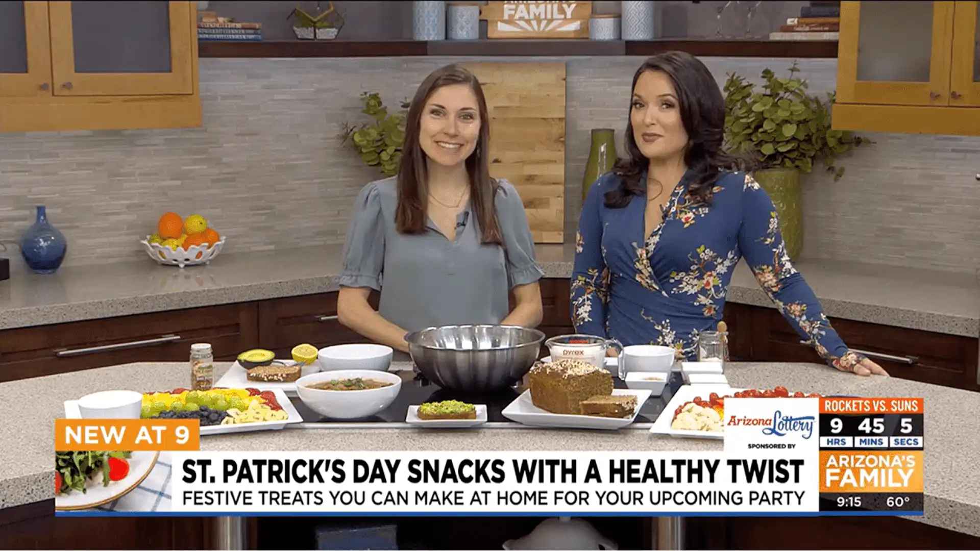 Two women in a TV kitchen at Village Clubs Camelback showcase healthy St. Patrick’s Day snacks, with Arizona’s Family logo visible.