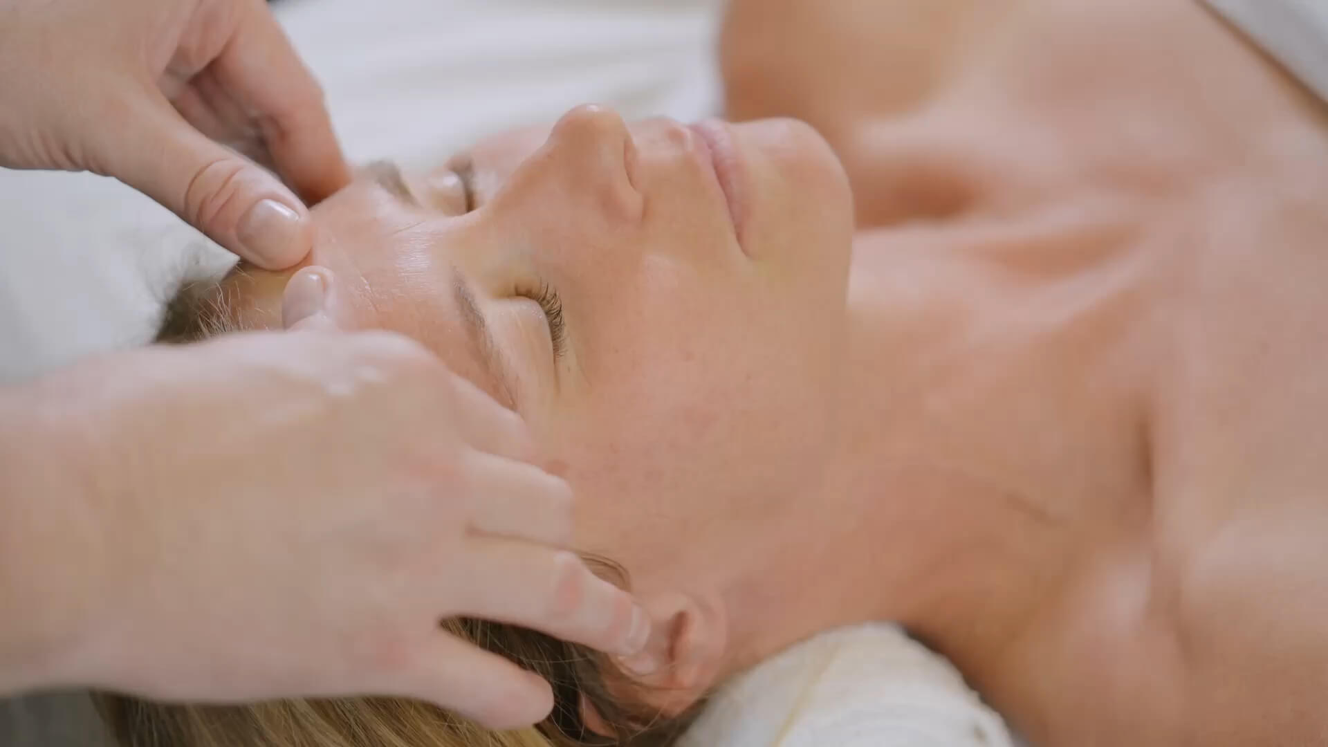 A guest enjoys a relaxing facial massage at Village Clubs Camelback spa, showcasing soothing professional care and comfort.