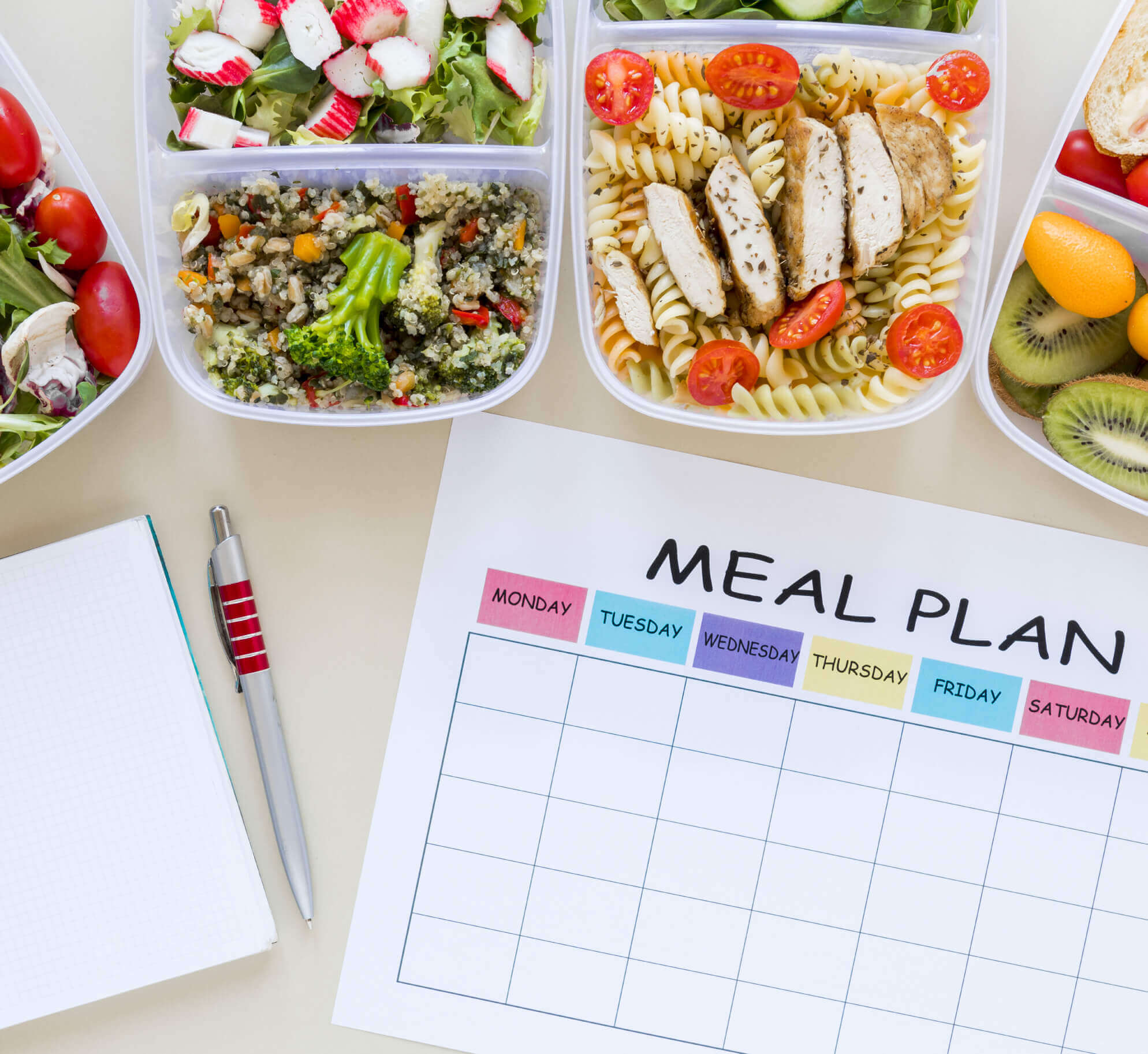 Village Clubs Camelback meal planning with a template, notebook, and healthy packed meals like salad, quinoa, and fruit on table.