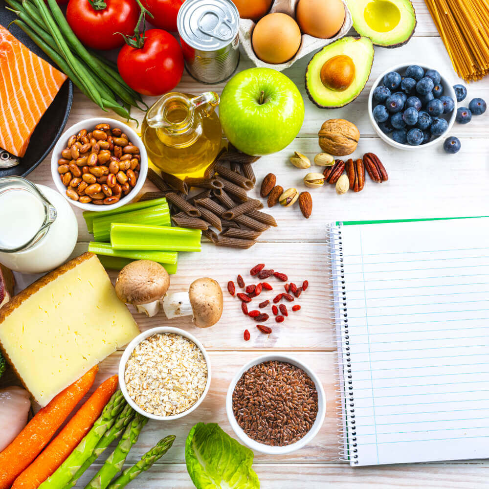 Healthy foods surround a notepad at Village Clubs Camelback, highlighting nutrition resources at the Arizona facility.