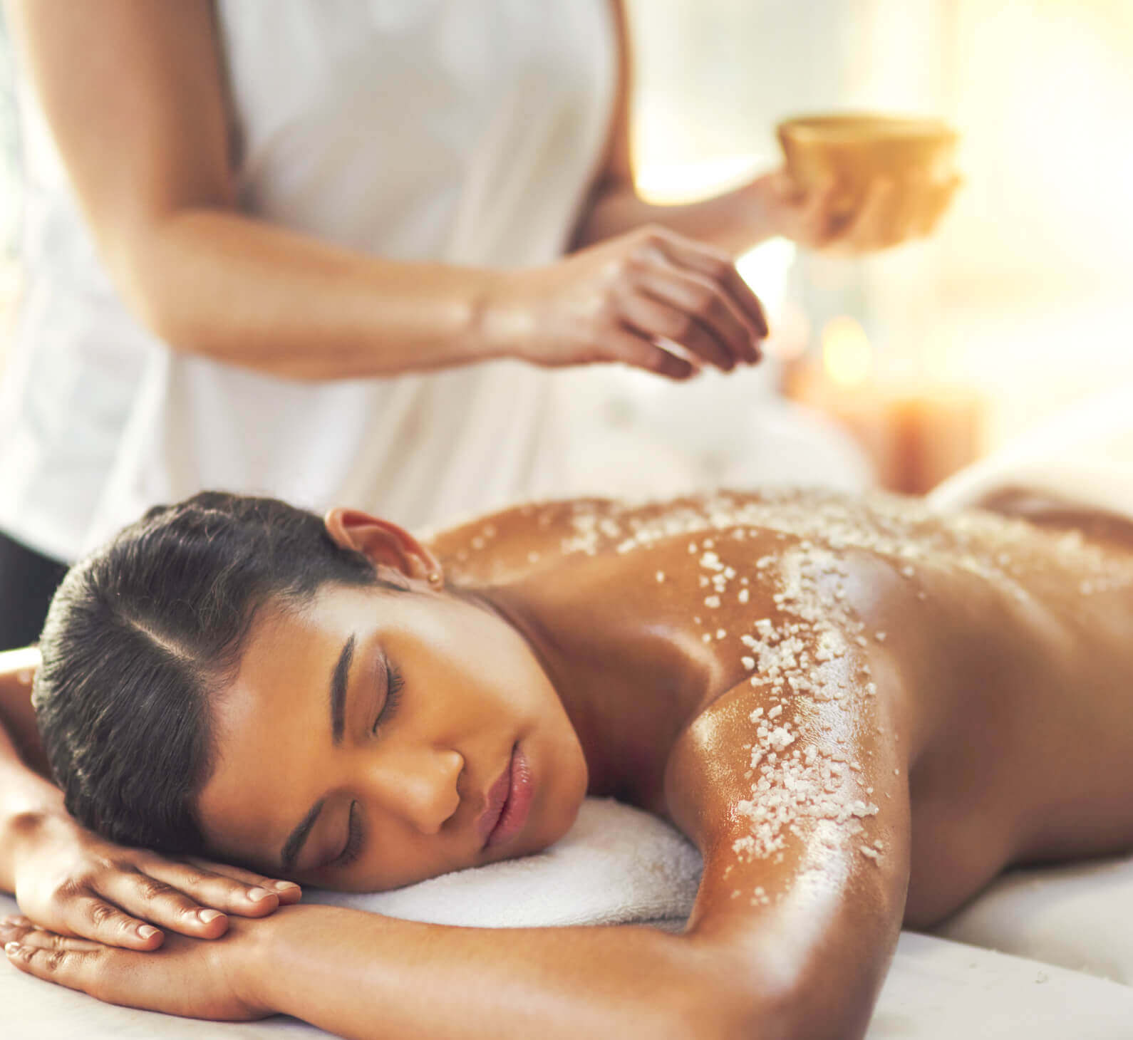 At Village Clubs Camelback Spa, a woman enjoys a soothing sea salt scrub as part of relaxing massage services in Arizona.